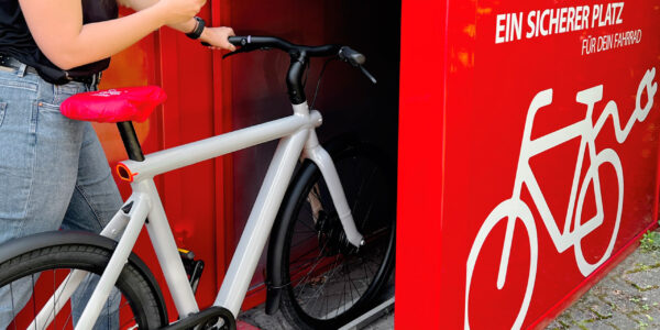 Eine junge Frau stellt ein Fahrrad mithilfe der mobilet-App in eine Fahrradbox