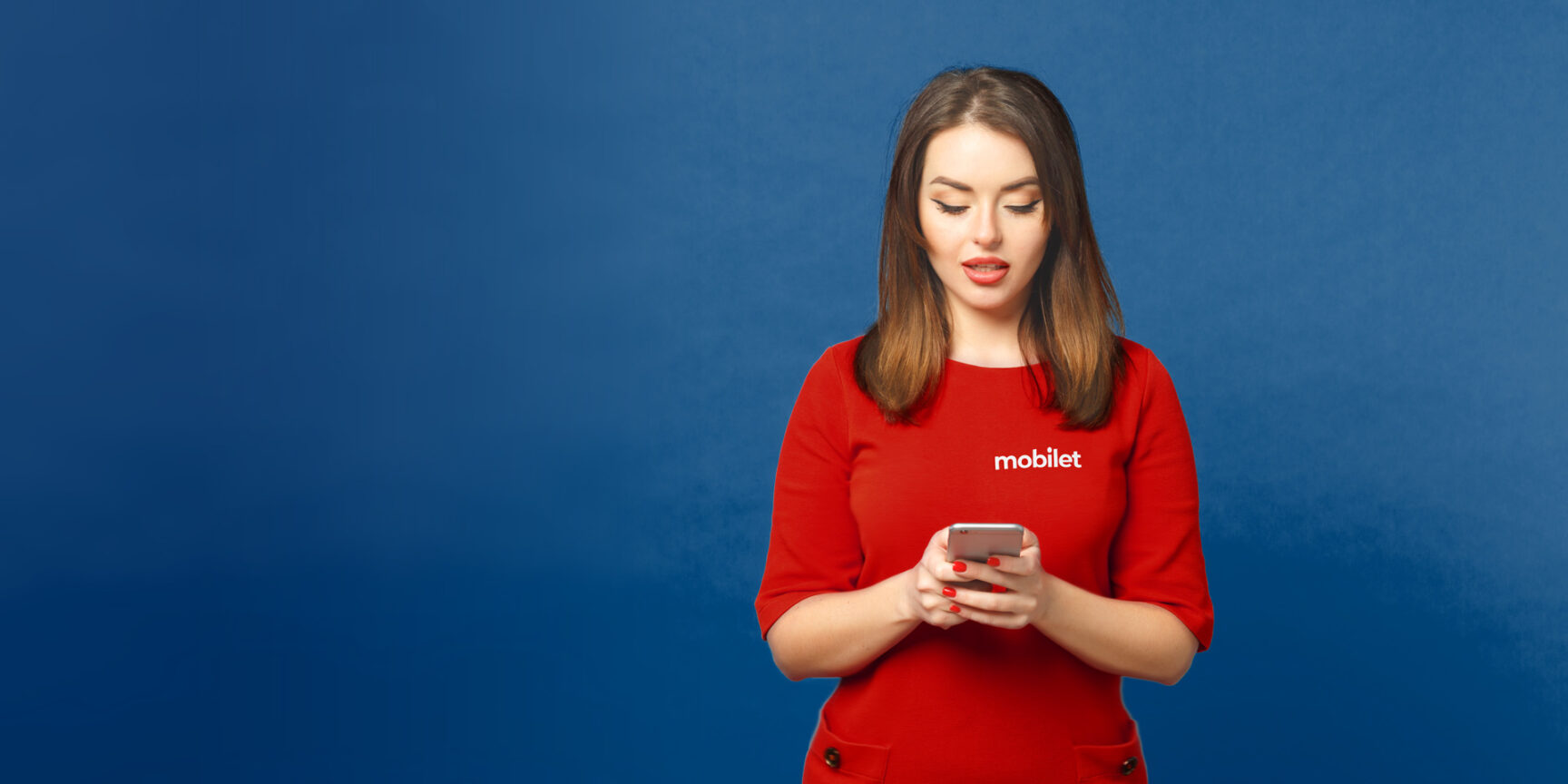 Dziewczyna w czerwonej bluzce korzysta ze smartfona poszukując informacji na temat usług Mobilet